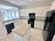 Bright kitchen features white cabinets, black appliances, an island, and a view into the dining area at 2558 Grandville Ave, Henderson, NV 89052