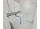 Functional laundry room with white cabinets, tile floor, washer, and dryer for household convenience at 2558 Grandville Ave, Henderson, NV 89052