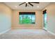 Cozy bedroom showcases neutral carpet, ceiling fan, and a window offering an inviting outdoor view at 26 Sun Mirage Ave, Henderson, NV 89011