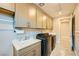 Convenient laundry room is complete with upper cabinets, sink, and black front load washer and dryer at 26 Sun Mirage Ave, Henderson, NV 89011