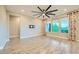 Open living room with wood-look tile floors, ceiling fan, and bright windows with stylish curtains at 26 Sun Mirage Ave, Henderson, NV 89011