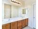 Bathroom featuring double sinks with wood cabinets, a large mirror, and updated lighting at 2713 Rue Toulouse Ave, Henderson, NV 89044