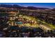 Night aerial shot of clubhouse with a pool, lush landscaping, tennis courts, and mountain backdrop at 2740 Billy Casper Dr, Las Vegas, NV 89134