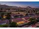 Scenic aerial view showcases homes with tile roofs in a well-maintained neighborhood with mountain views at dusk at 2740 Billy Casper Dr, Las Vegas, NV 89134