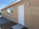 Exterior view of side of home with white door, two windows, and neutral stucco at 3016 Mount Charleston Dr, Pahrump, NV 89048