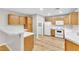 Bright kitchen boasts wood cabinets, white appliances, laminate flooring, and adjacent laundry room at 3676 Renovah St # 102, Las Vegas, NV 89129