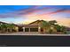 Charming single-story home boasts a three-car garage and lush landscaping under a vibrant sunset sky at 3870 Valles Caldera Ct, Las Vegas, NV 89118