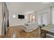 Cozy living room featuring hardwood floors, a modern sofa, and large windows providing ample light at 4432 Vicobello Ave, Las Vegas, NV 89141
