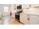 Modern kitchen features stainless steel appliances, white cabinets, quartz countertops, and herringbone wood flooring at 4707 Pink Jasper Ct, Las Vegas, NV 89141
