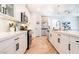 Bright kitchen boasts white cabinets, stainless appliances, pendant lights, quartz counters, and herringbone wood floors at 4707 Pink Jasper Ct, Las Vegas, NV 89141