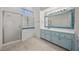 Bathroom with dual sinks, tiled mirrors, light blue cabinets, and shower-tub combo at 5148 Forest Oaks Dr, Las Vegas, NV 89149