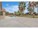 A tranquil backyard featuring a beautiful pool, lush green lawn, and mature palm trees under a bright blue sky at 5889 Taylor Valley Ave, Las Vegas, NV 89131