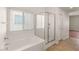 Bright bathroom featuring a soaking tub with shower, glass door, and tile floor at 6512 N Bruce St, North Las Vegas, NV 89086
