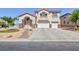 Two-story home with three-car garage, desert landscaping, and stone accents on the columns at 6638 Dazzling Heights Ln, Las Vegas, NV 89110
