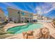 Inviting in-ground pool surrounded by palm trees and a stone border, creating a relaxing backyard oasis at 664 Mystic Cliffs Ave, Las Vegas, NV 89183