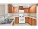 Kitchen featuring wooden cabinets, stainless steel double sink, and white appliances at 6680 Caporetto Ln # 103, North Las Vegas, NV 89084