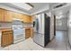 Bright kitchen features wooden cabinets, white appliances, stainless steel refrigerator, and tile flooring at 7084 Burcot Ave # D27, Las Vegas, NV 89156