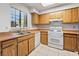 Well-lit kitchen with wooden cabinets, white appliances, and a stainless steel sink under a window at 7084 Burcot Ave # D27, Las Vegas, NV 89156