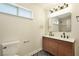 Bathroom with a long wood double sink vanity, modern mirrors and lighting, and a geometric patterned floor at 744 Willow Ave, Henderson, NV 89002