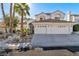 Elegant two-story home with a three-car garage, mature palm trees, and manicured desert landscaping at 8125 Sunset Cove Dr, Las Vegas, NV 89128