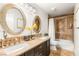Bathroom featuring dual sinks, elegant mirrors, and a tiled shower-tub combo at 8801 Rozetta Ct, Las Vegas, NV 89134