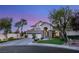 Elegant two-story home with a three-car garage, manicured lawn, and mature trees against a picturesque evening sky at 8801 Rozetta Ct, Las Vegas, NV 89134