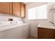 Bright laundry room features a washer, dryer, cabinet storage, sink and window at 9044 Crimson Clover Way, Las Vegas, NV 89134