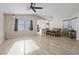 Spacious living room with wood-look tile flooring, ceiling fan, and natural light flowing in from large windows at 9284 Lopseed Ct, Las Vegas, NV 89149