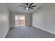 Bright bedroom with gray carpet, ceiling fan, and sliding glass doors leading to a balcony at 9436 Mount Cash Ave # 101, Las Vegas, NV 89129