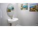 Chic powder room with a pedestal sink, round mirror, and decorative artwork at 1130 Calico Rdg, Mesquite, NV 89034