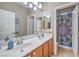 Bright bathroom features double sinks, wood cabinets, and a shower with a decorative curtain at 664 Blue Crystal Creek Rd, Henderson, NV 89002
