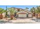 Charming two-story home featuring a three-car garage and meticulously landscaped front yard with palm trees at 664 Blue Crystal Creek Rd, Henderson, NV 89002