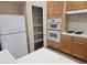 Spacious kitchen with light wood cabinets, a white refrigerator, double ovens, and a walk-in pantry for storage at 9324 Pitching Wedge Dr, Las Vegas, NV 89134