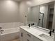 Elegant bathroom featuring dual sinks, a soaking tub with marble surround, and modern fixtures at 3240 Walker River St, North Las Vegas, NV 89032