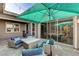 Inviting back patio with a turquoise umbrella, stone pavers and comfortable outdoor seating at 10004 Terrastone Dr, Las Vegas, NV 89148