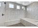 Close-up of tub and shower area with white marble-style tiling and a built-in bench at 10004 Terrastone Dr, Las Vegas, NV 89148