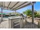 Beautiful backyard featuring a complete outdoor kitchen under a shaded pergola, with views of the pool and mountains at 10004 Terrastone Dr, Las Vegas, NV 89148