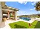 Beautiful outdoor living space featuring a pool with waterfall, putting green, and covered patio at 103 Reflection Cove Dr, Henderson, NV 89011
