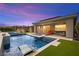Luxurious backyard pool featuring in-pool seating, a fire pit, outdoor lounge area, and lush greenery at 103 Reflection Cove Dr, Henderson, NV 89011