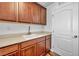 Charming laundry room with wooden cabinets, stainless steel sink, and white door to complement the space at 10611 Auburn Springs Ave, Las Vegas, NV 89166
