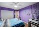 This bedroom has wood flooring, a ceiling fan, and purple paint at 11117 Romola St, Las Vegas, NV 89141