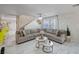 An open-concept living area featuring a comfortable sectional, white tile flooring, and neutral decor with a glimpse of the staircase at 11117 Romola St, Las Vegas, NV 89141