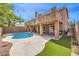 Inviting backyard featuring a sparkling pool, covered patio, balcony, artificial grass and a privacy fence, perfect for outdoor relaxation at 1112 Caraway Ln, Las Vegas, NV 89144