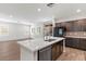 Modern kitchen featuring a center island with a sink, dark wood cabinetry, and stainless steel appliances at 127 Medianoche St, Las Vegas, NV 89138