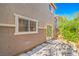 Private backyard with a covered patio area, mature shrubs, and an exterior window at 137 Desert Pond Ave, Henderson, NV 89002