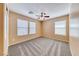 Cozy bedroom with neutral walls, a ceiling fan, carpeted floor and three windows letting in natural light at 173 Calm Morning Ave, Henderson, NV 89002
