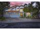 Charming home exterior with a three-car garage, beautiful landscaping, and warm sunset lighting at 176 Tierra Bonita Ct, Henderson, NV 89074
