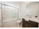Bright bathroom features a tub with a white marble surround, a sliding glass door, and dark cabinets with a white countertop at 19 Desert Ivy Ln, Henderson, NV 89011