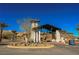 View of the community entrance with modern architecture, desert landscaping, and palm trees at 19 Desert Ivy Ln, Henderson, NV 89011