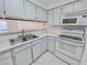 Well-lit kitchen with white cabinets and appliances, including a stainless steel sink and view into adjoining living space at 2044 Mesquite Ln # 202, Laughlin, NV 89029